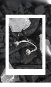 Macro view of S925 sterling silver horseshoe ring with geometric balls on black charcoal