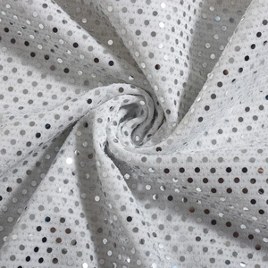 Vue détaillée de paillettes argentées sur tissu blanc montrant l'éclat métallique