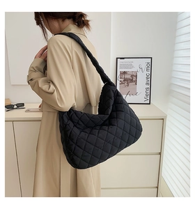 Detail view of black quilted cloud bag with knotted shoulder strap worn by a model