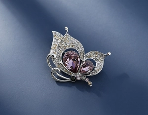 Macro detail of butterfly brooch with purple crystals and champagne rhinestones