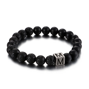 Lava stone bead bracelet with silver cube metal letter M charm on white background