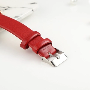 Close-up of red leather watch strap featuring a silver stainless steel buckle with fine texture