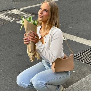 Gilet en maille blanche avec boutons associé à un jean bleu clair et un sac à chaîne