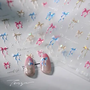 Detail of 3D bow nail stickers with iridescent finish on pink gradient manicured nails
