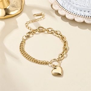 Macro shot of 18K gold plated asymmetric chain bracelet with heart pendant on a desk
