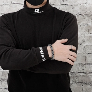 Close-up of a silver stainless steel cross chain bracelet on a male model's wrist