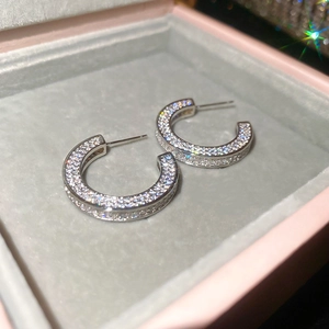 Detailed macro view of C-shaped silver earrings with sparkling cubic zirconia inlay