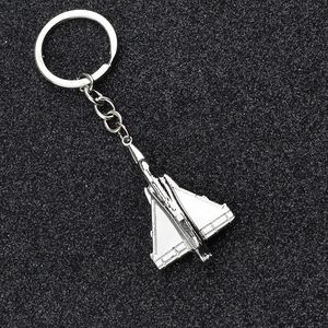 Polished silver metal fighter jet keychain model on a textured black background