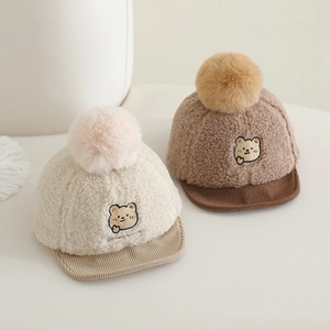 Détail de bonnets d'hiver en peluche pour bébé avec broderie d'ours et pompons doux