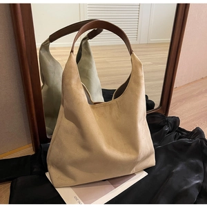 Macro detail of beige suede hobo bag with brown leather strap and mirror reflection