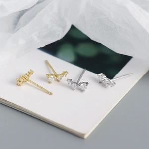 Detailed macro view of gold and silver S925 geometric stud earrings with tiny crystals
