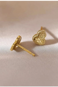Detailed macro view of S925 sterling silver stamp on golden heart textured earrings