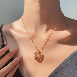 Detail of MOM heart pendant with projection stone on gold chain worn by a model