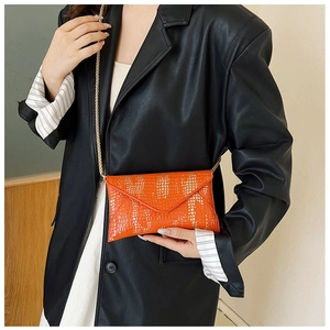 Macro view of orange crocodile texture faux leather bag with elegant gold chain strap