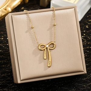 Collier élégant en acier inoxydable doré avec pendentif nœud perlé sur fond noir