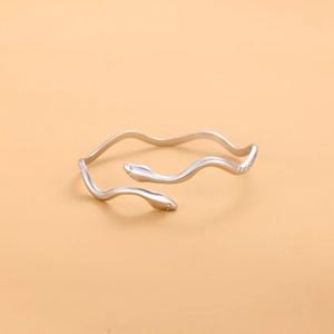 Detailed macro view of minimalist silver snake-shaped bangle with wave curves and open ends