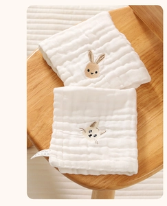 Close-up of soft white cotton gauze baby bibs with cute rabbit and cat embroidery detail
