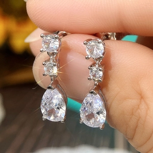 Macro shot of silver teardrop earrings with triple-stone cubic zirconia in claw setting