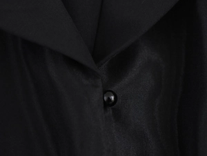 Détail macro d'une robe en organza montrant un bouton noir et la texture du tissu