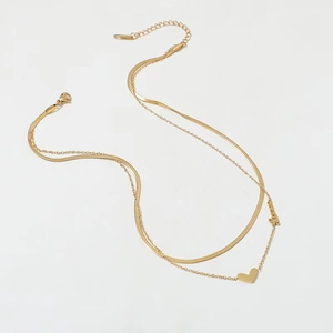 Détail du collier double rang en acier titane doré avec pendentif cœur et love
