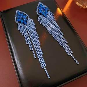 Detail shot of blue rhinestone floral earrings with long silver tassel on black leather