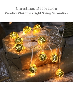 Detail of warm LED Christmas string lights with golden hollow metal spheres on gift box