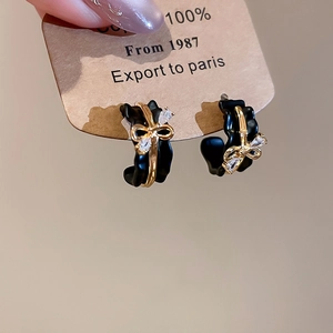 Detail of 18k gold plated bow earrings with black enamel finish and marquise rhinestones