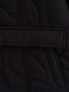 Close-up of black cotton jacket featuring detailed wave pattern quilting and sewing texture