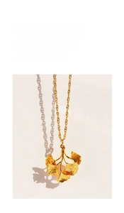 Detailed macro shot of a golden ginkgo leaf pendant necklace with fine vein textures