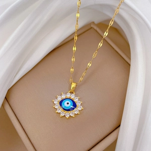 Détail du collier œil maléfique doré avec pierres bleues sur fond en soie blanche