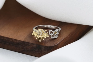 Macro view of honeycomb ring with gold bee and yellow gemstone on wood