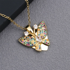 Detail of a gold butterfly necklace featuring colorful zircons on textured grey stone