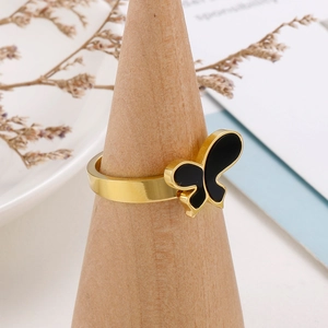 Macro d'une bague papillon dorée sur support en bois avec décor floral élégant