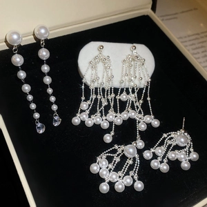 Detailed view of three elegant pearl tassel earrings with silver chains on black velvet