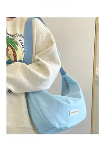 Dettaglio borsa hobo in nylon celeste con tracolla larga e piccola etichetta del marchio