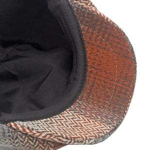 Detail of herringbone pattern tweed cap with smooth interior lining and neat stitching