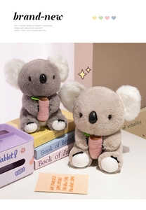 Detail of plush koala dolls in grey and brown holding pink accessories on a soft background