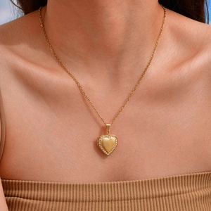 Detail of a gold heart locket necklace with sparkling diamonds worn by a model