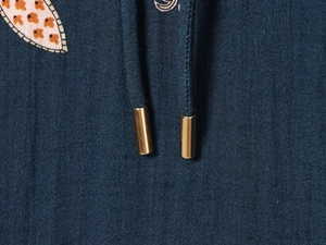 Détail macro des cordons bleu foncé avec embouts métalliques dorés polis sur le sweat