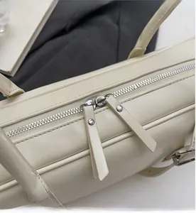 Macro detail showing smooth silver double metal zippers with leather pullers on cream bag