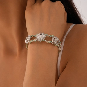 Detailed shot of braided sunflower bangle featuring silver sun and rose metal charms