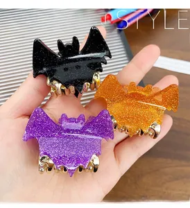 Detail of bat-shaped glitter acrylic hair claws in black, purple, and orange colors