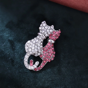 Close-up of pink and white crystal twin cat brooch with intertwined heart-shaped tails