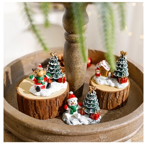 Miniature resin Christmas figurines with reindeer and snowman on a rustic wooden tray
