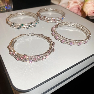 Close-up of stacked open bracelets with sparkling pavé zircons in pink and green colors