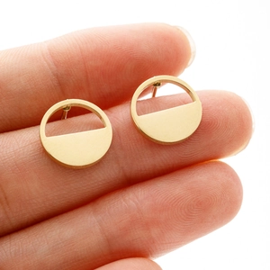 Close-up of a tiny golden geometric round earring held by fingers for scale