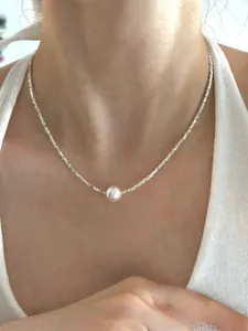 Close-up of S925 sterling silver necklace with white pearl on a model's collarbone