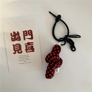 Detail view of red and black checkered fabric knot charm with black lanyard and cat tag
