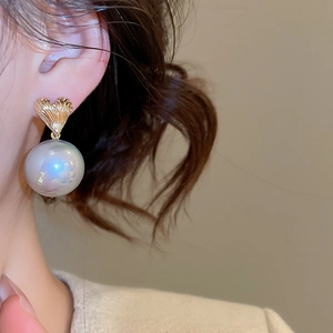 Close-up of elegant gold heart earrings with iridescent round pearls on a model