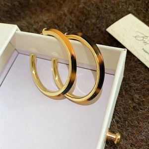 Close-up of C-shaped tortoiseshell acetate earrings showing the S925 silver stamp